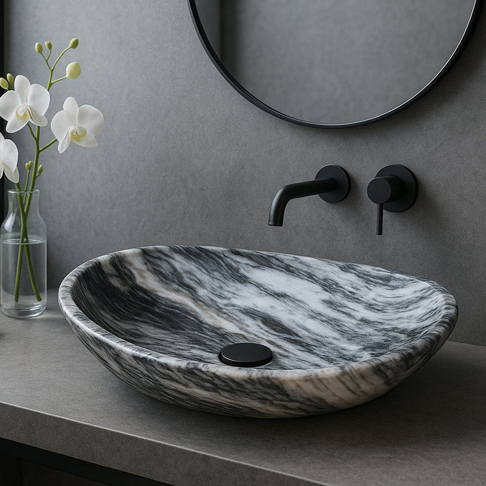 Marble sink on a bathroom counter with a vase of flowers and towels.