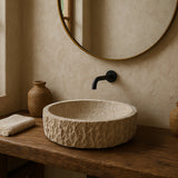 Bathroom with travertine stone sink, wooden vanity, and round mirror.