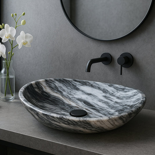 Marble sink on a bathroom counter with a vase of flowers and towels.