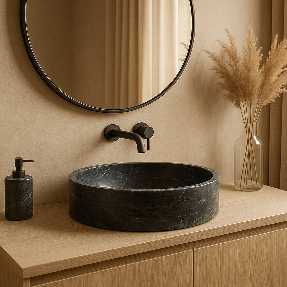 Bathroom vanity with black sink, round mirror, and decorative elements.